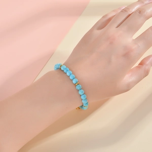Detail of 6mm turquoise stone bead bracelet with gold spacers on woman's wrist