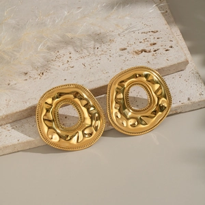 Golden donut irregular earrings with hammered texture on beige stone blocks
