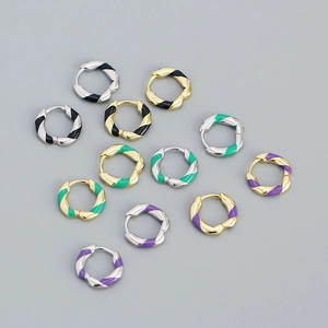Detail view of colorful enamel spiral hoop earrings in green, purple, and black tones
