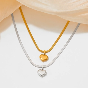 Elegante Halsketten mit Herzanhängern in Gold und Silber auf feinem Seidenstoff