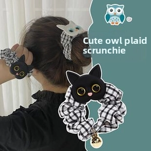 Detail view of black and white checkered hair scrunchie with cute owl and gold bell