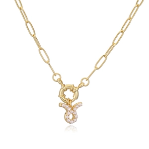 Macro detail of gold-plated paperclip chain with Taurus zodiac pearl pendant