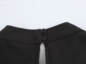 Detailansicht des schwarzen Rückenausschnitts mit zwei Knöpfen am Faltenkleid