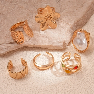 Detailed view of bohemian gold rings with pearls on natural stone display