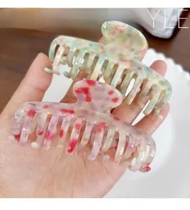 Detail of large acetate hair claws with marble texture held by a hand in two colors