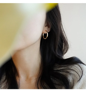 Elegante primo piano di una modella che indossa orecchini a cerchio dorati minimalisti