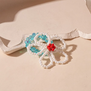 Detail view of handmade glass flower ring with white petals and blue crystal band