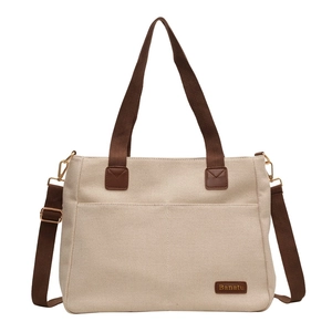 Large beige canvas tote bag with brown straps and front pocket for daily commute