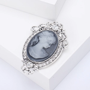 Vintage silver brooch with lady relief and clear crystals on white geometric display