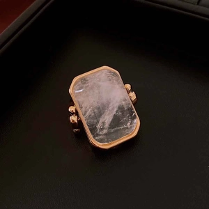 Makroaufnahme eines rechteckigen Edelsteinrings mit goldenen Perlen auf schwarzem Leder