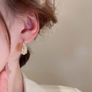 Detailed view of luxury gold zircon purse-shaped hoop earrings worn by a model
