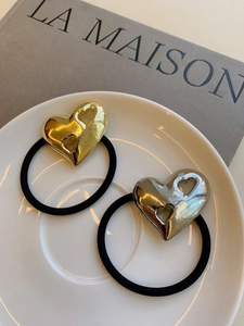 Detail of high-elastic black hair ties with textured gold and silver metal heart charms