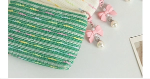 Detail of woven texture storage pouches with pink bow and pearl zipper pendants