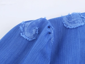 Vue macro des détails du tissu bleu usé avec bords à franges sur la robe mini