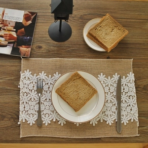 Rectangle jute placemat with white floral lace trim on dark wood table setting