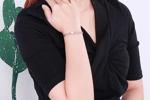 Close-up of heart-shaped rose gold bracelet with white shell inlay on model's wrist