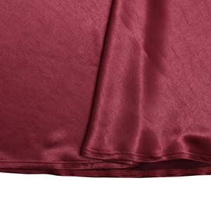 Detail of dark red satin dress showing smooth fabric texture and hemline stitching