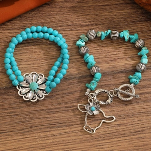 Detail of turquoise bracelet set with bull head charm and flower pendant on wood background