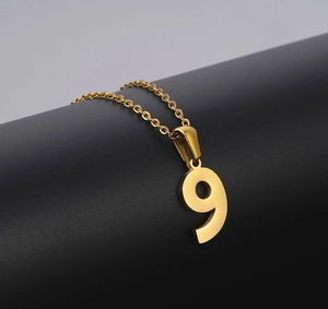 Close-up of golden number 9 pendant necklace on professional black matte background