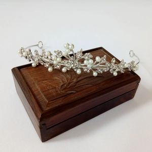 Elegant silver bridal tiara with pearls and rhinestones on vintage wooden box