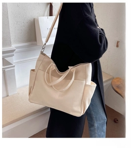 Detail of canvas tote bag showing side pockets and adjustable wide shoulder strap