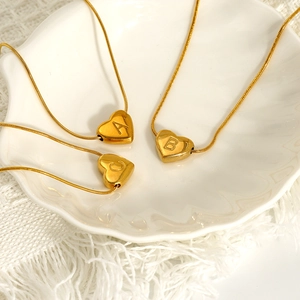 Polished gold heart initial necklace with A, B, C engraving on white shell plate