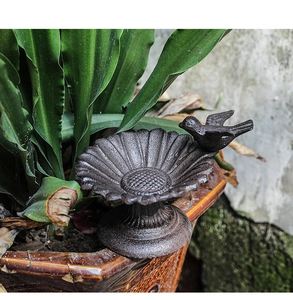 Close-up of vintage cast iron sunflower bird feeder with a small bird figurine