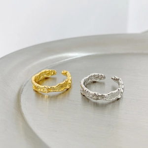 Detail of two irregular textured S925 sterling silver open rings in gold and silver
