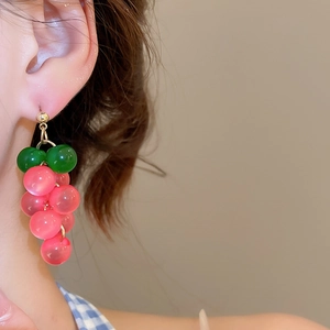 Detail of pink resin grape cluster drop earrings with gold needle on a model