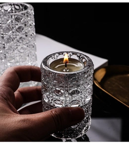 Close-up of diamond pattern glass candle holder with a glowing candle in hand