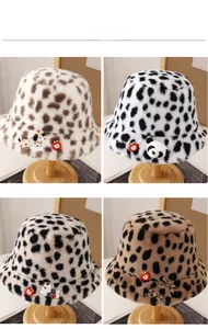 Detail of four leopard print plush bucket hats with cute cartoon patches on wooden stands
