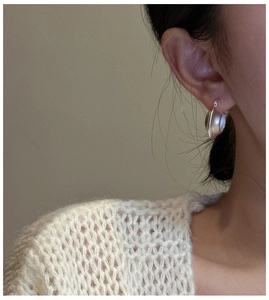 Close-up detail of silver matte finish hoop earrings worn with cozy knitwear