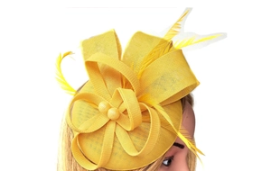 Close-up of yellow fascinator hat with mesh texture and delicate feather details