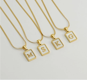 Macro detail of 18K gold stainless steel necklaces with white shell alphabet pendants