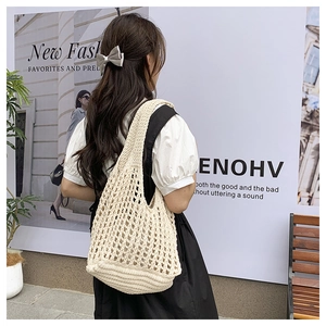 Detailed knit texture of off-white hollow mesh beach tote bag shown on shoulder