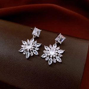 Close-up of silver snowflake earrings with micro-set zircons on dark leather