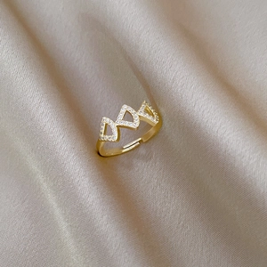 Adjustable gold ginkgo leaf ring with sparkling crystals on champagne silk background