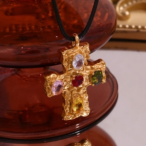 Macro shot of 18K gold cross pendant with five colorful oval gemstones on black cord