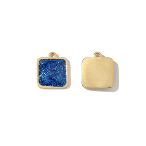 Macro shot of square gold-plated steel pendants with sparkling blue inlay and smooth back