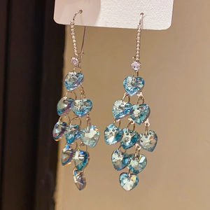 Detail of silver needle earrings featuring cascaded blue heart-shaped crystal tassels