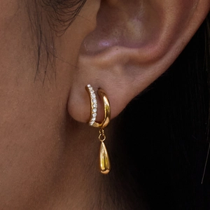 Gros plan de boucles d'oreilles double C dorées avec zircons brillants et pendentif goutte