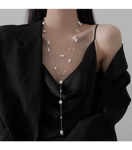 Close-up of irregular baroque pearl long necklace layered on a stylish black blazer