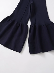 Close-up of navy blue knit trousers with delicate ruffled hems and ribbed texture