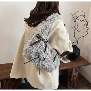 Detail of grey fluffy shoulder bag featuring brown leather bows on soft faux fur