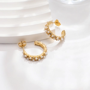 Detail of 18k gold C-shape earrings with inlaid pearls and sparkling cubic zirconia stones