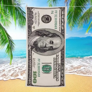 Microfiber beach towel with 100 dollar bill print hanging on a tropical beach background