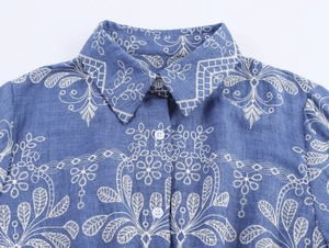 Détail de la robe bleue de style pastoral avec broderies florales blanches et revers