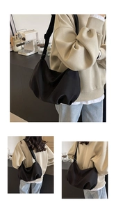 Detail of adjustable wide shoulder strap on a black nylon crossbody dumpling bag