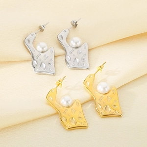 Detailed view of gold and silver irregular geometric earrings with white pearls on silk