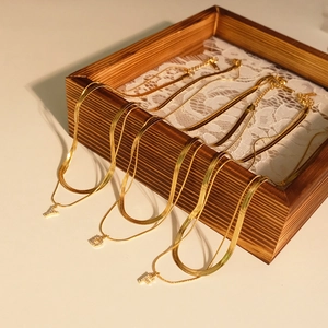 Detail of gold double-layered snake chains with rhinestone-embedded Y, D, F initial pendants